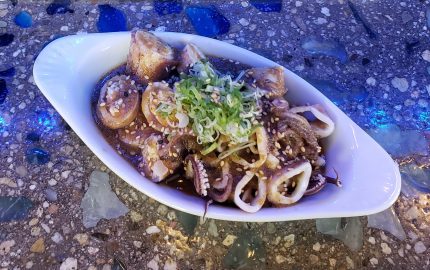 Cooked baby squid, stuffed with crab, submerged in a ginger sauce