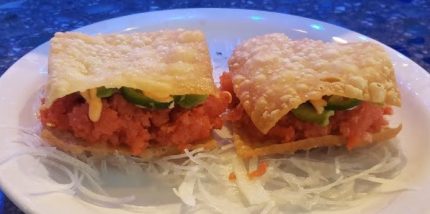 2 pieces of a spicy tuna mix, with avocado inside a crispy wonton shell, topped with a spicy mayo sauce and a sliced jalapeno